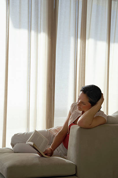 istock Relaxed Woman Reading Book On Sofa 491610827