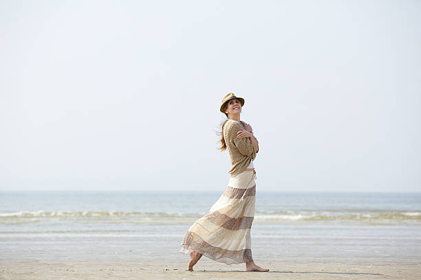istock Woman smiling and walking on the beach 491612561