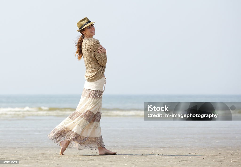 Donna sorridente cammina sulla spiaggia - Foto stock royalty-free di Camminare