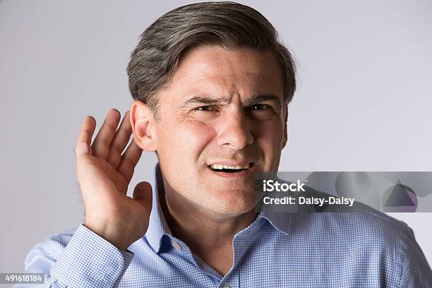 Studio Shot Of Man Suffering From Deafness Stock Photo - Download Image Now - Listening, Hearing Aid, Deafness
