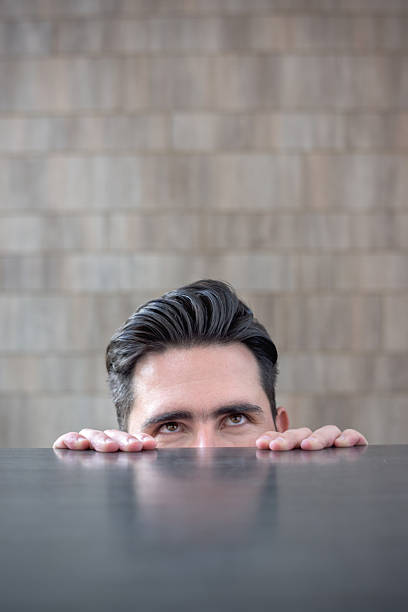 istock Business man thinking and peeking over a table 491619724