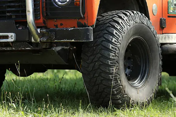 front wheel of an old orange Land-Rover Discovery with with SUV tire