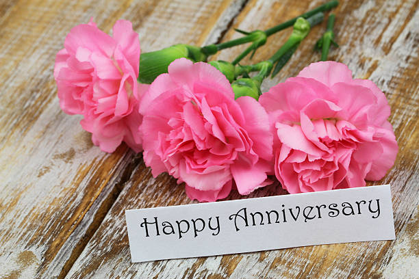 istock Happy Anniversary card with three pink carnations on rustic wood 491620788