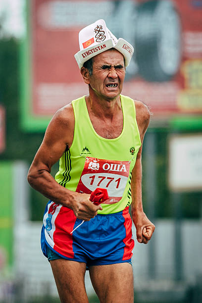Omsk, Russia -  September 20, 2015: old man athlete running last effort during Siberian international marathon