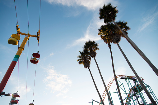 Santa Cruz, California, USA - May 15, 2015: The amusement park in Santa Cruz opens the last week of May every year. This picture taken in mid May shows an empty amusement park during the afternoon. Focus on the Cable Railway together with some palm trees and a roller coaster.