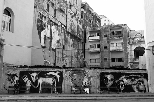 Havana, Cuba - August 10, 2015: Graffiti and architecture in Old Havana street. People sit on a bench and wait for the bus.