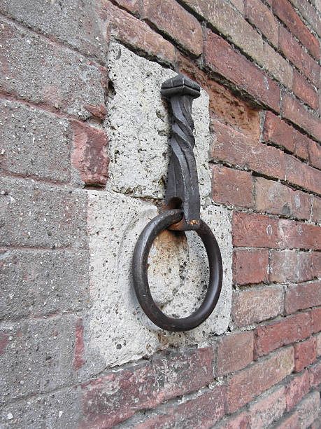 istock Ancient iron hoop hanging on stone wall 491631494