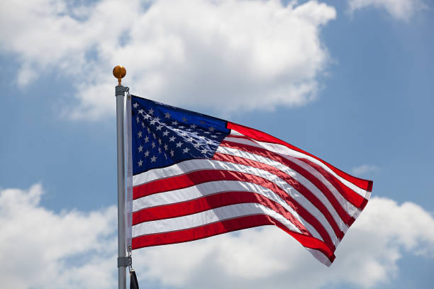 istock American flag against blue cloudy sky 491633408