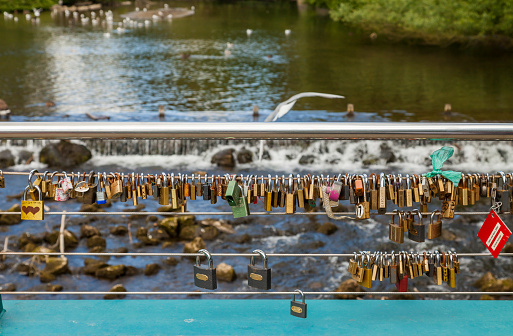 Bakewell, Derbyshire, England, UK - July 19, 2015: Love locks attached to the cable on weir bridge, Bakewell, Derbyshire, England, UK,