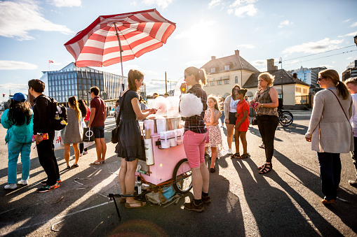 Oslo, Norway - July 20, 2015: Woman making and selling cotton candy on Oslo Street. 