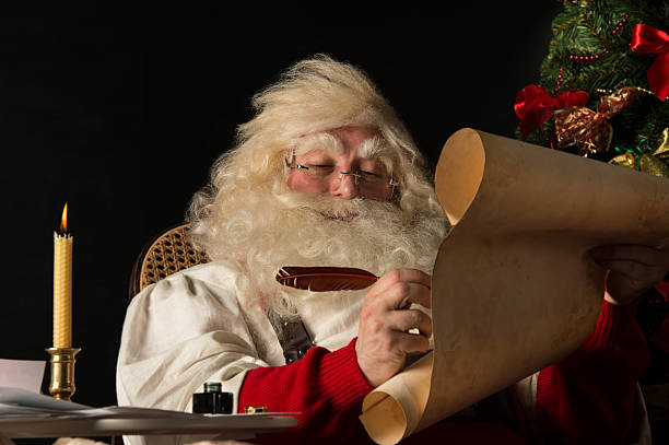 istock Santa Claus sitting at home and writing on paper roll 491635586