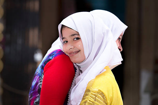 Cheerful and happy Muslim women with traditional veil embracing each other on the occasion of Eid.