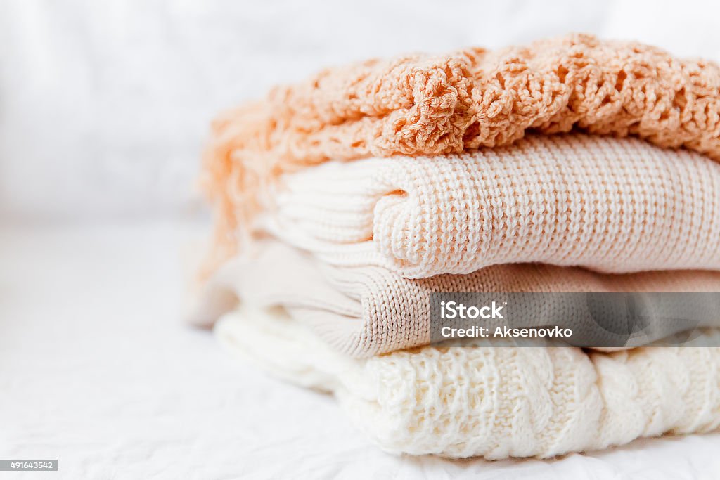 Pila de ropa beige woolen sobre un fondo blanco. - Foto de stock de Jersey - Top libre de derechos