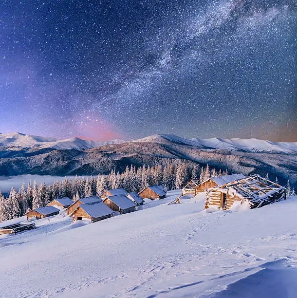 Photo of chalets in the mountains at night under the stars