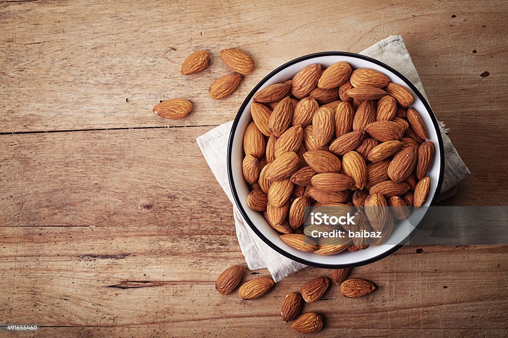 Almonds White bowl of almonds on wooden background Almond Stock Photo