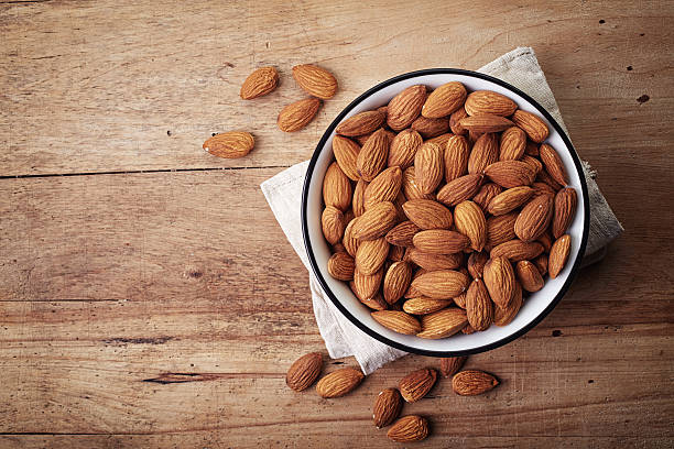 Almonds White bowl of almonds on wooden background almond stock pictures, royalty-free photos & images