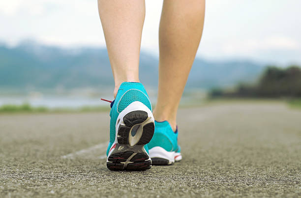 istock Runner athlete feet running on road under sunlight. 491656034