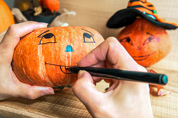 istock Woman paints the pumpkin for Halloween celebration. 491659690