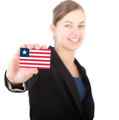 business woman holding a card with the flag of Liberia. With focus on the card