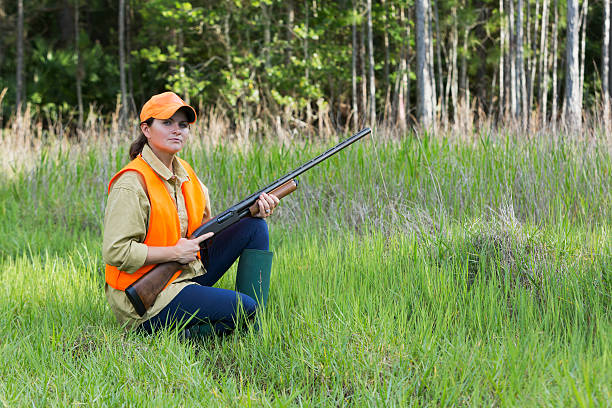 istock Female hunter with shotgun kneeling in tall grass 491668852