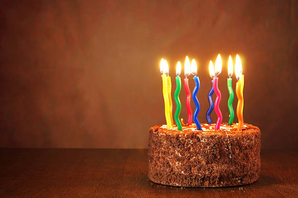 istock Birthday chocolate cake with burning candles on brown background 491671564