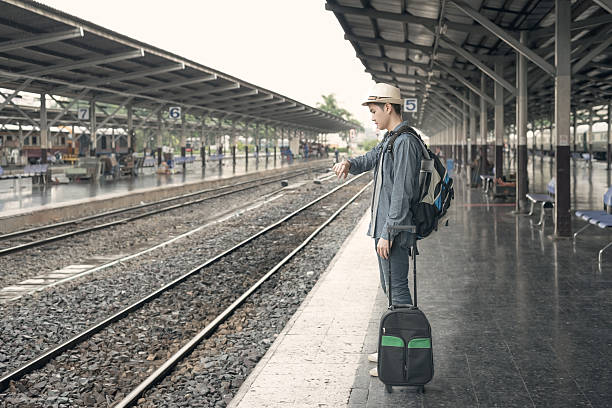 istock Train delay. Young asian man looking in his watch 491672574