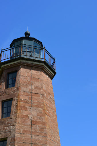Point Judith, Narragansett, Rhode Island: Point Judith Lighthouse with the light on the fresnel lens - entrance to Narragansett Bay - octagonal granite tower and sky - photo by M.Torres