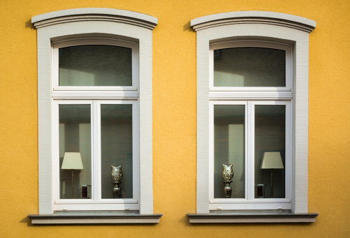 Two identical ornated windows at the facede of a yellow hous