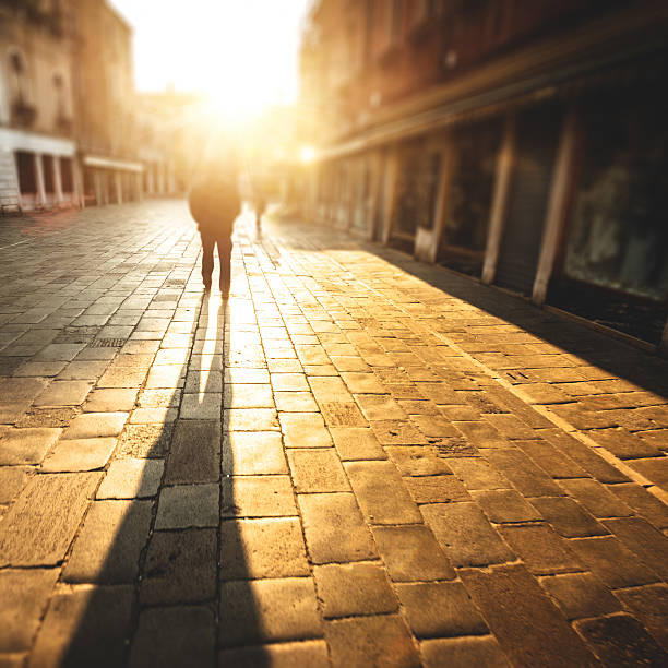 istock backlit of man walking on the cobblestone 491683155