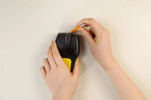 Photo of Using Stud Finder on interior home wall