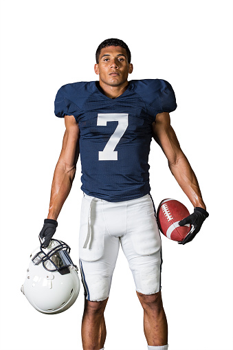 Portrait of a strong muscular American Football Player isolated on white. Stoic and talented African American athlete holding a ball and a helmet