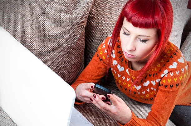 レッドヘッドタイプのテキストメッセージの女性彼女のスマートフォン - teenager problems typing teenagers only ストックフォトと画像