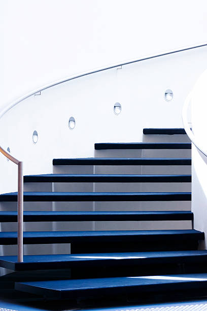 istock Modern black staircase with handrail on white wall, copy space 491685021