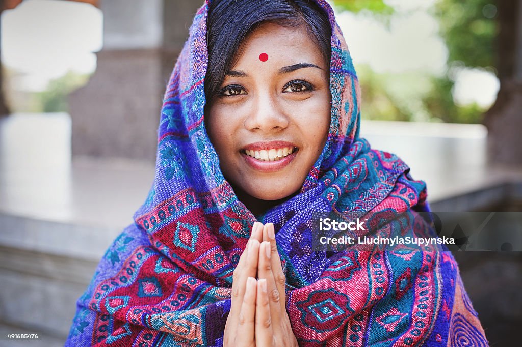 beautiful nepalese woman  performing namaste gesture Young women in colored headscarf keepung her hands in "namaste" Nepal Stock Photo