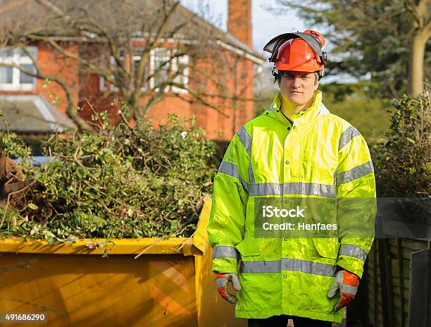 Tree Surgeon In Front Of Skip Full Of Tree Cuttings Stock Photo - Download Image Now