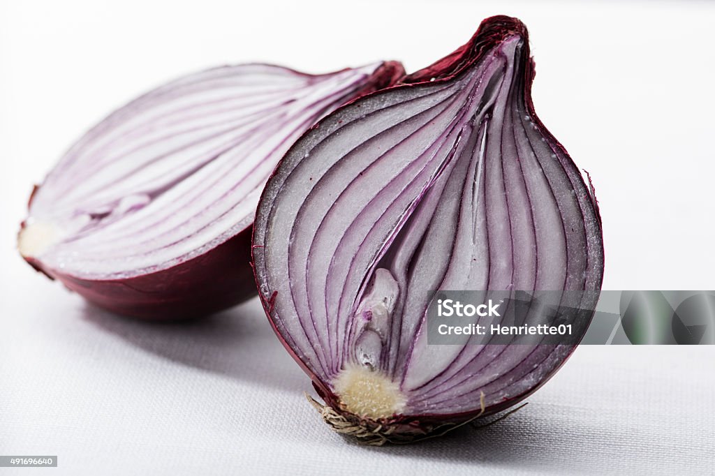 Two halves of a red onion on white A red onion cut in two parts, lying on a white tablecloth 2015 Stock Photo