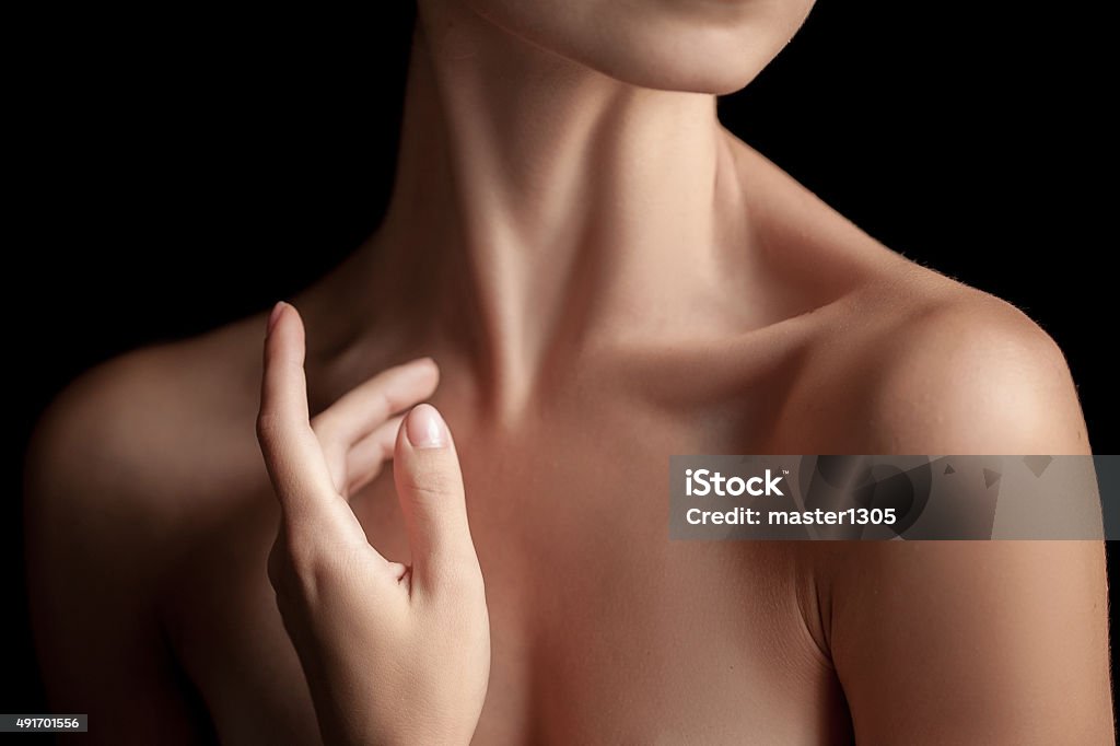 The close-up of a young woman's neck The close-up of a young woman's neck and hands  on dark background Women Stock Photo