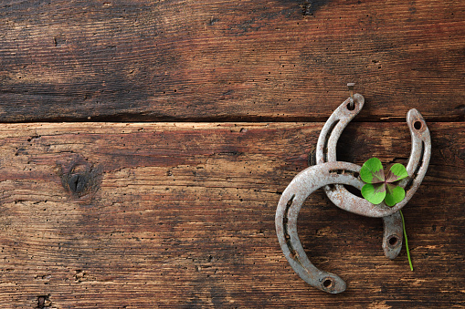 St. Patricks day, lucky charms. Two horseshoes with a four leaved clover on wooden board