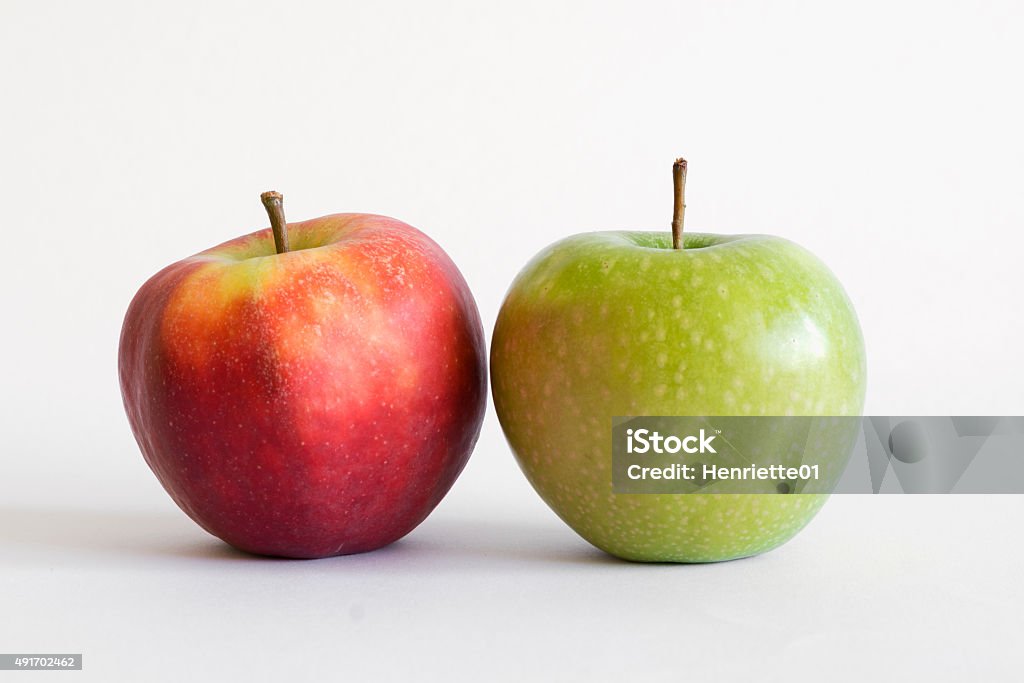 Red and green apple on white A red apple and a green apple standing next to eachother 2015 Stock Photo