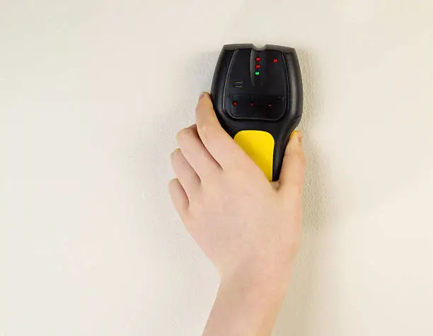 Photo of Electronic Stud Finder against interior wall of home
