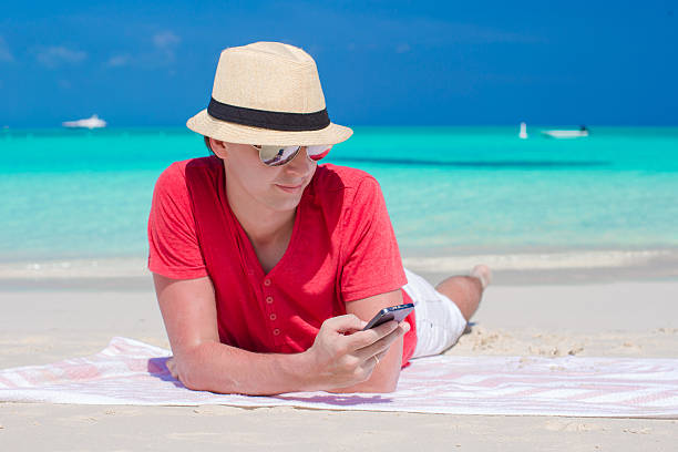istock Young man with phone on tropical white beach 491703627