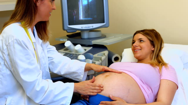 Doctor pressing hands on a pregnant womans stomach