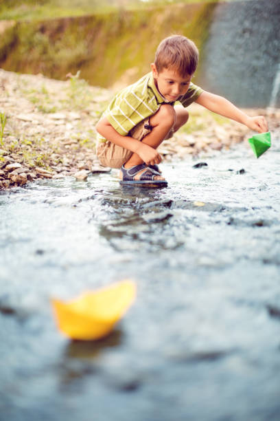 istock Boy playing paper boats on the river 491708424