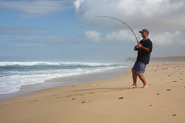 Man surf fishing from the Sea shore Man fishing from the sea shore with fishing rod sea fishing stock pictures, royalty-free photos & images