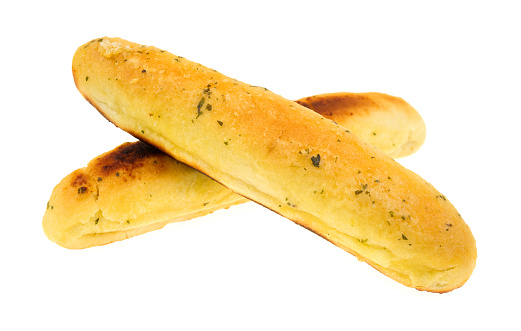 Two garlic bread sticks with one cooked perfectly and the other burnt on a white background.