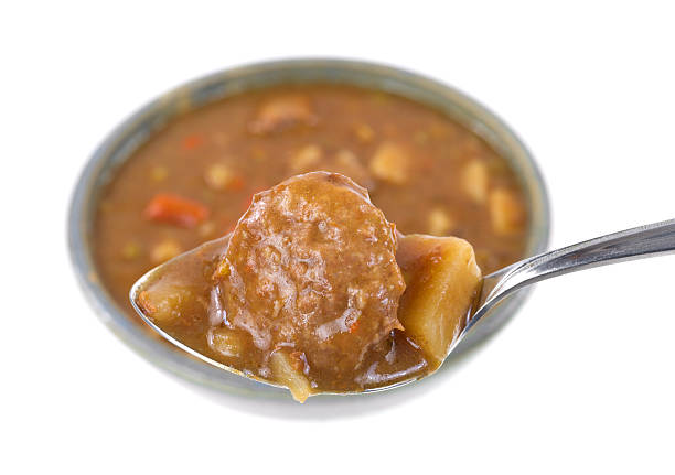 Meatball and potatoes on a spoon with meal in background