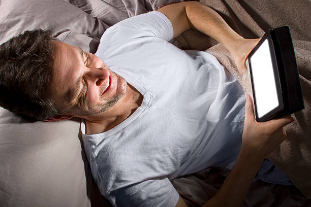 istock Male in Bed Browsing the Internet with a Tablet 491725395