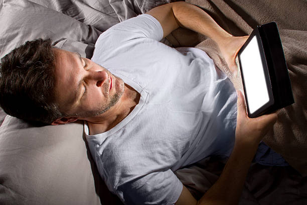 istock Male in Bed Browsing the Internet with a Tablet 491725403