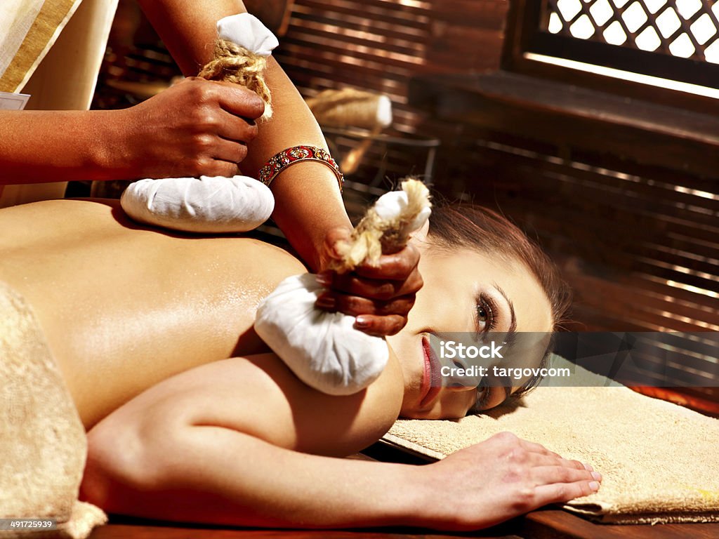 Woman having massage with pouch. Woman having Ayurveda massage with herbal ball. Adult Stock Photo