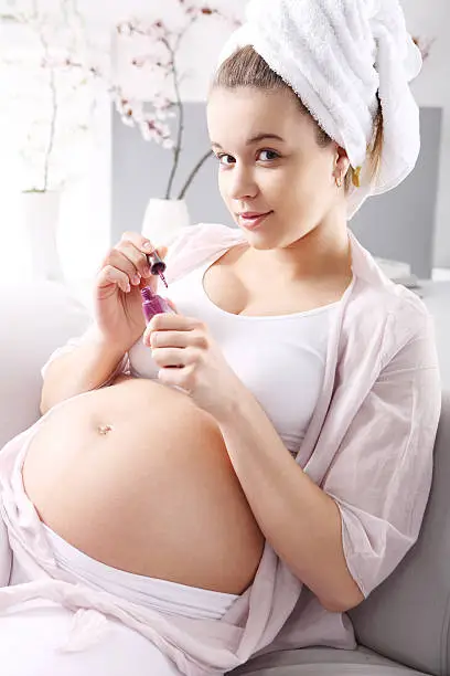 Photo of Beautiful pregnant woman painting nails